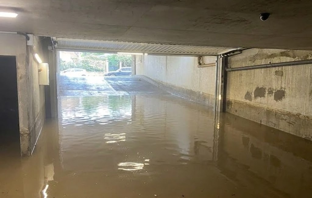 Un sous sol avec une porte de sortie ouverte et de l'eau boueuse qui commence à monter 